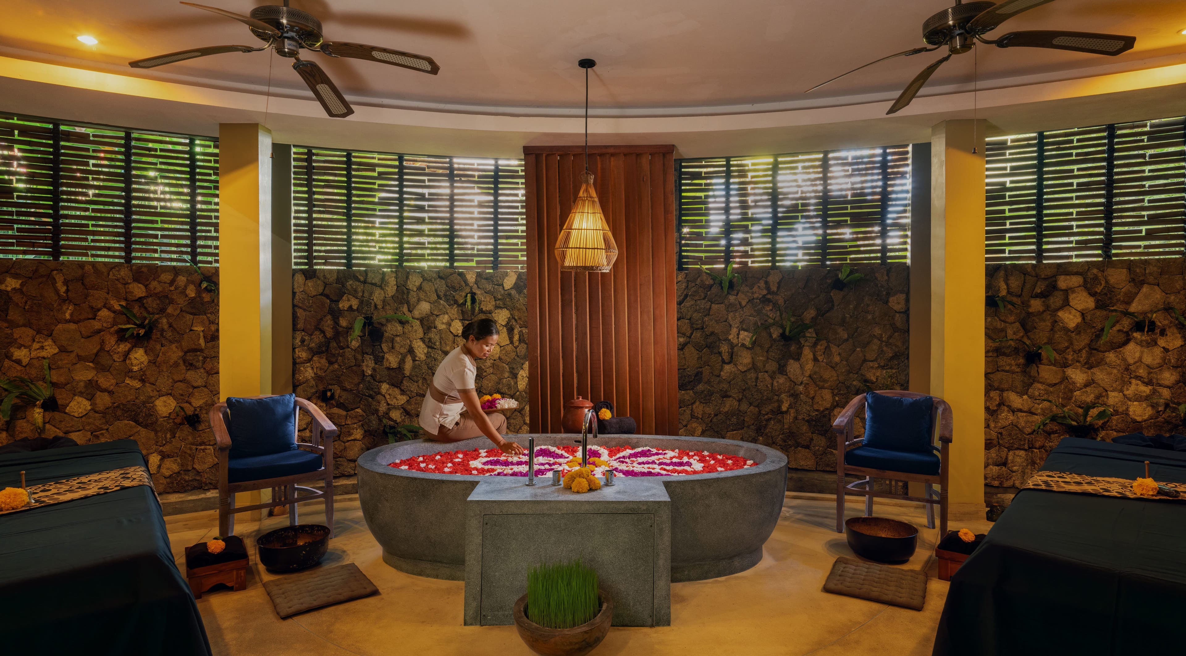 A therapist prepares a floral bath at Darbha Spa Ubud in Bali, Bali, ID, highlighting a serene and relaxing ambiance.