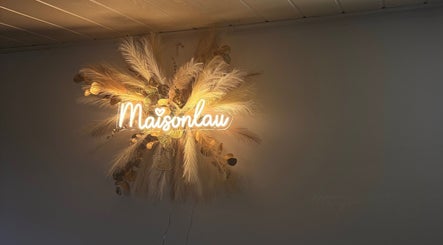 Enseigne lumineuse de MaisonLau, Vieux-Thann, Grand Est, FR, entourée de décorations florales.