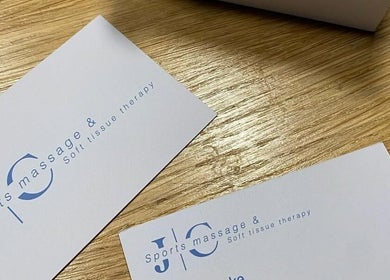 JC Sports Massage and Soft Tissue Therapy business cards on a wooden table in Chesterfield, England, GB.