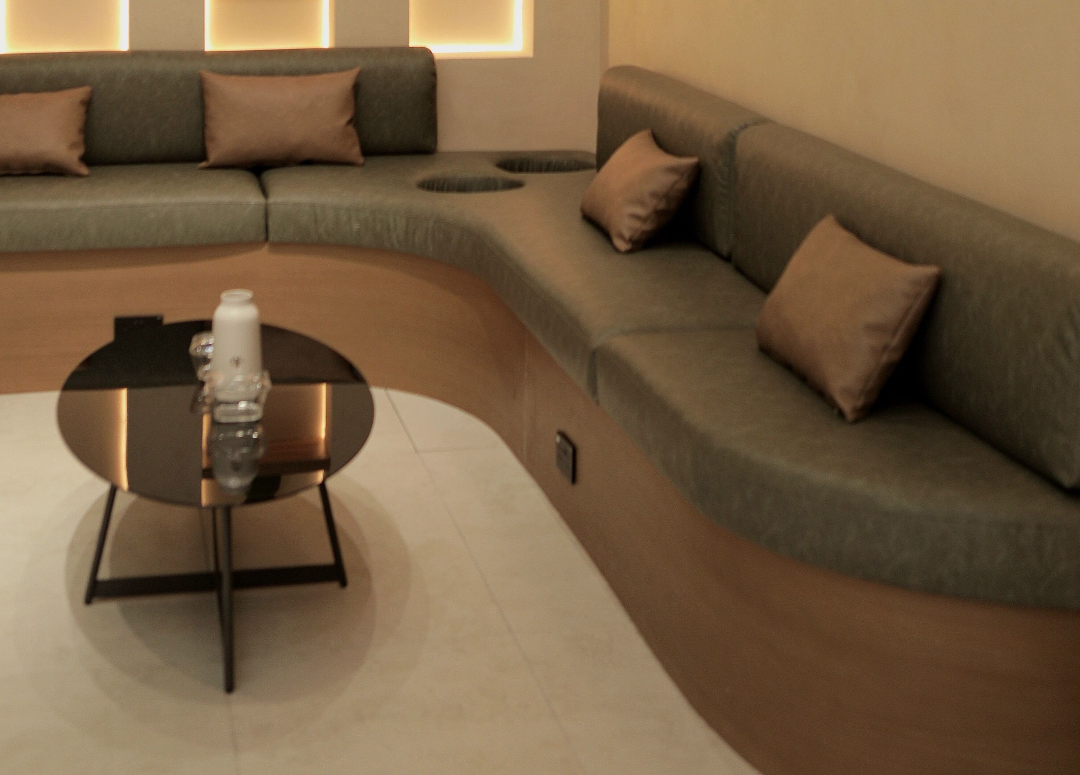 Elegant seating area in La Biche Beauty Salon, Abu Dhabi, AE featuring a curved sofa and sleek table.