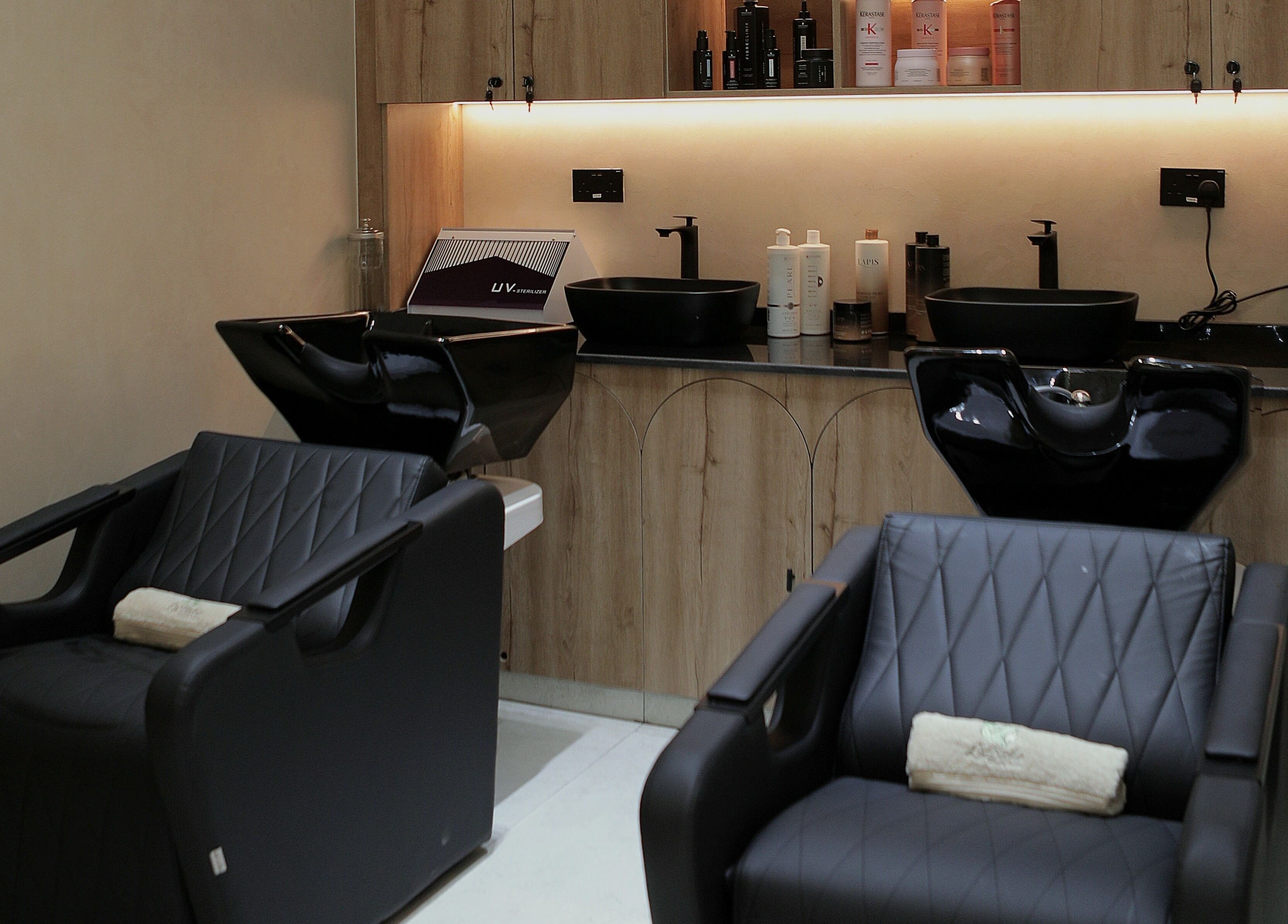 Modern styling stations at La Biche Beauty Salon in Abu Dhabi, Abu Dhabi, AE featuring elegant black chairs.