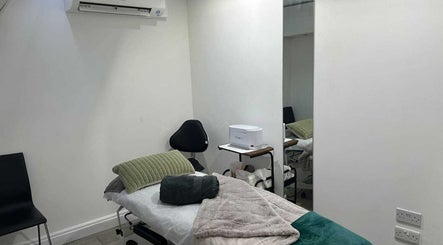 Cozy treatment room at Innior Ltd, Teddington, England with massage table and white walls.