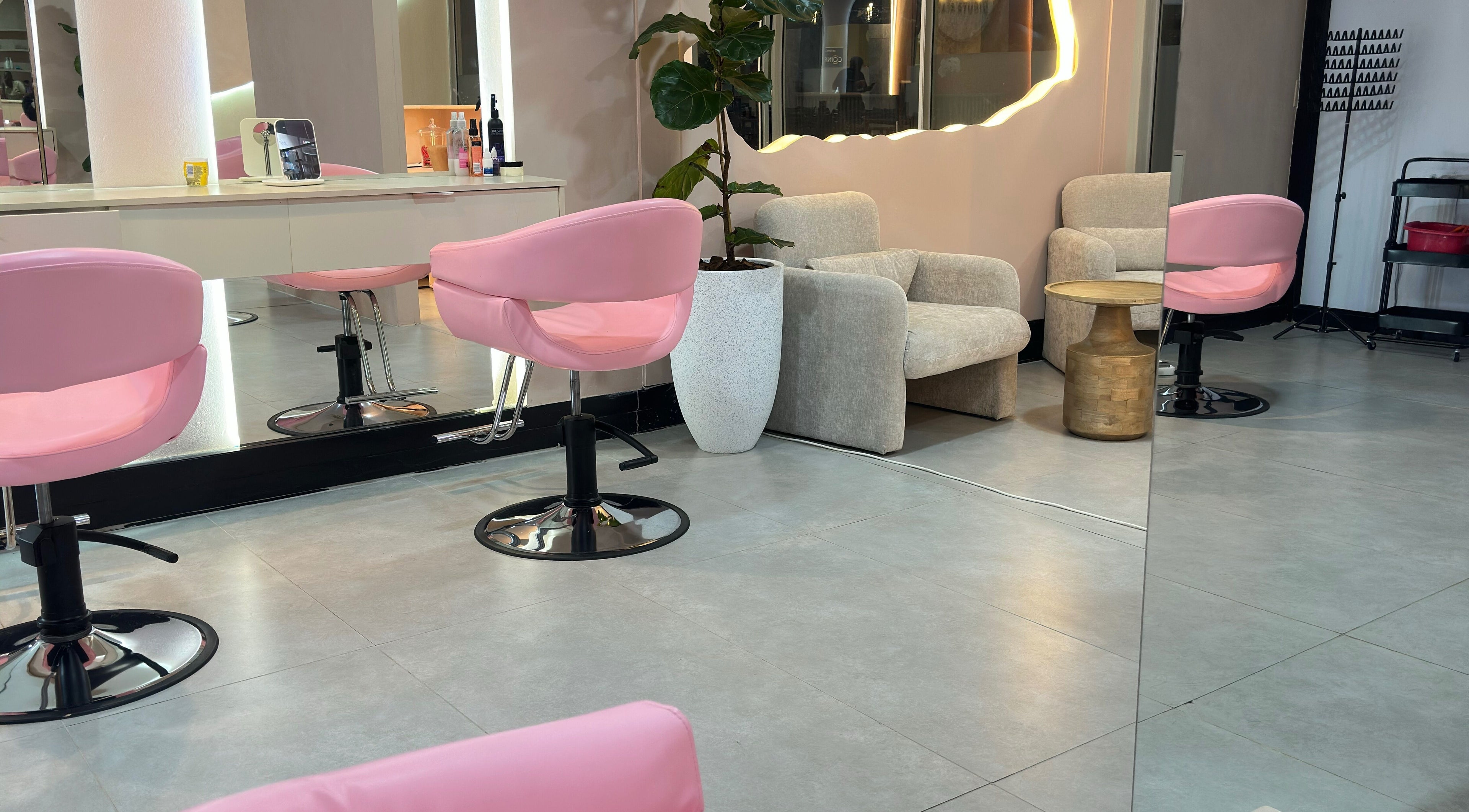 Modern interior of Londie London Hair Studio in Sandton, Gauteng, ZA, featuring pink chairs and stylish decor.