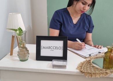 Recepcionista en Marccelo Láser, Buenos Aires, anotando datos en un ambiente acogedor.