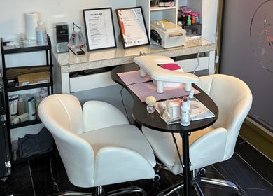 Nail care station at Stiletto Vault, Wembley, England, GB, showcasing cozy white chairs and manicure tools.