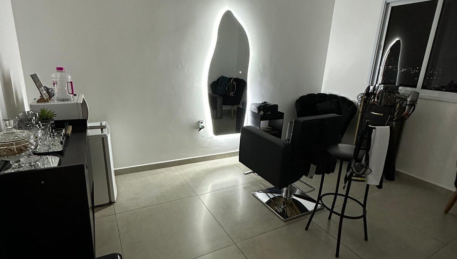 Ambiente elegante do Studio Valeska Carvalho, São Paulo, com espelho iluminado e cadeira de cabeleireiro.