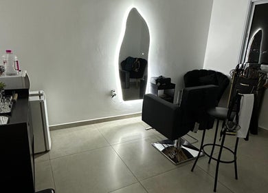 Ambiente elegante do Studio Valeska Carvalho, São Paulo, com espelho iluminado e cadeira de cabeleireiro.