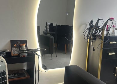 Espelho iluminado no Studio Valeska Carvalho, São Paulo, São Paulo, BR, refletindo cadeiras e equipamento de beleza.