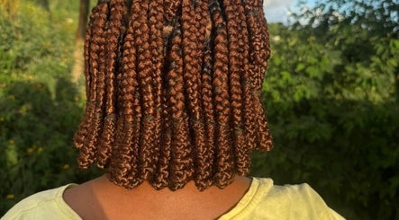 Intricate braids showcased at Hair .Byann, Kingstown, VC amidst lush greenery.