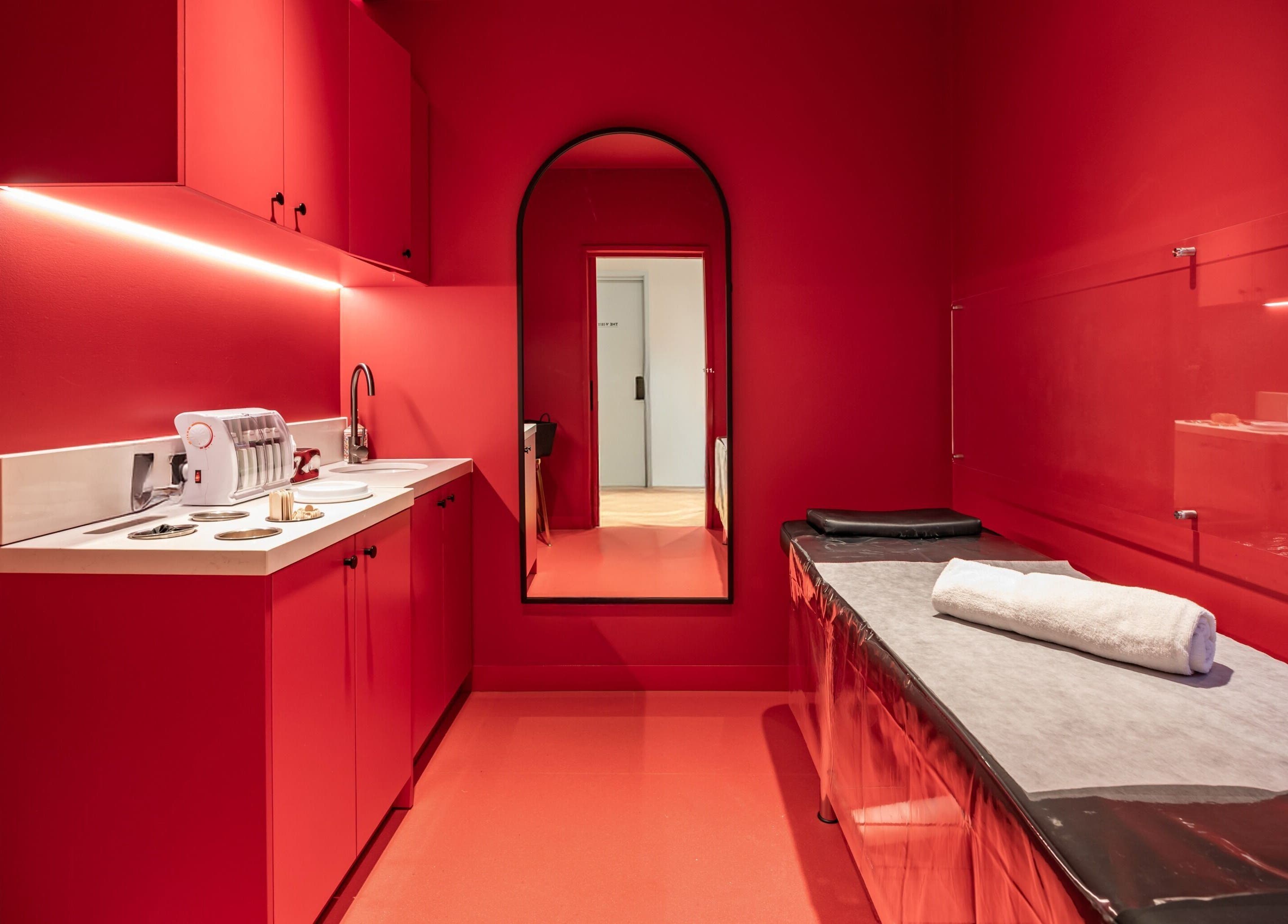 Elegant red treatment room at My Julie, Moonee Ponds, Victoria, AU, featuring a massage table and sleek decor.