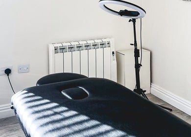 Treatment room at The Brow Rehab, Little Lever, England, GB with a black massage table and ring light.