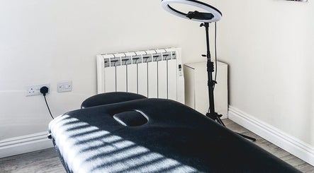 Treatment room at The Brow Rehab, Little Lever, England, GB with a black massage table and ring light.