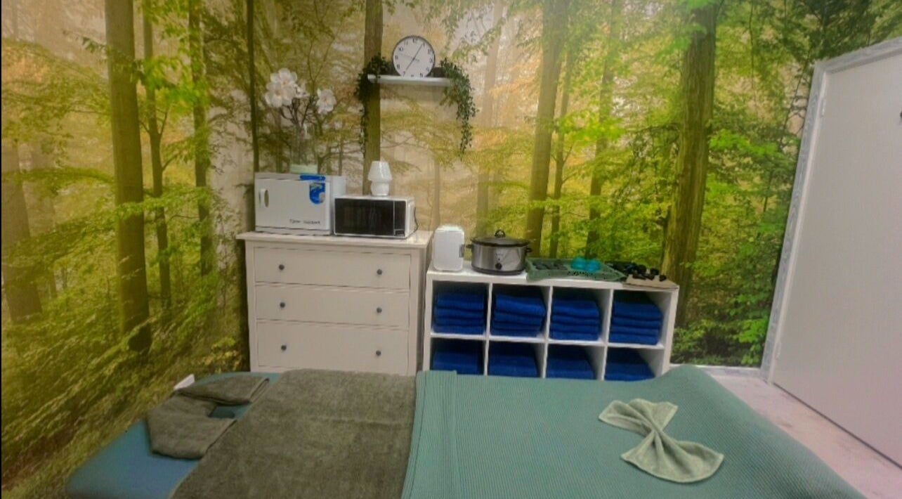 Tranquil massage room at Reborn Massage by Dwi, Cooloongup, WA, styled with forest wall art and relaxing decor.