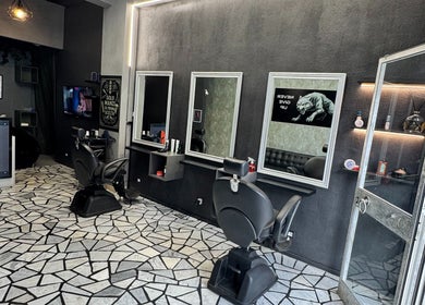 Interno elegante di G barber shop a Roma, Lazio, IT, con specchi moderni e poltrone per cliente.