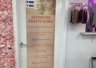 Entrance of Aesthetic Beauty Clinic in Kingston Upon Thames, England, GB, featuring a floral wall and treatment list.