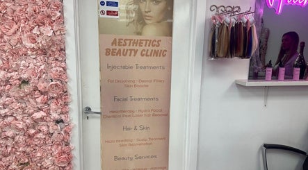 Entrance of Aesthetic Beauty Clinic in Kingston Upon Thames, England, GB, featuring a floral wall and treatment list.