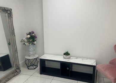 Chic decor at Aesthetic Beauty Clinic in Kingston Upon Thames, England, with ornate mirror and pink chair.