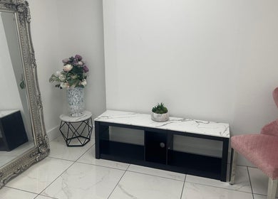 Chic decor at Aesthetic Beauty Clinic, Kingston Upon Thames, England, GB featuring a pink chair and ornate mirror.