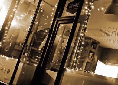 Illuminated exterior of REFINED BARBERSHOP, Paignton, England, GB with decorative lights.