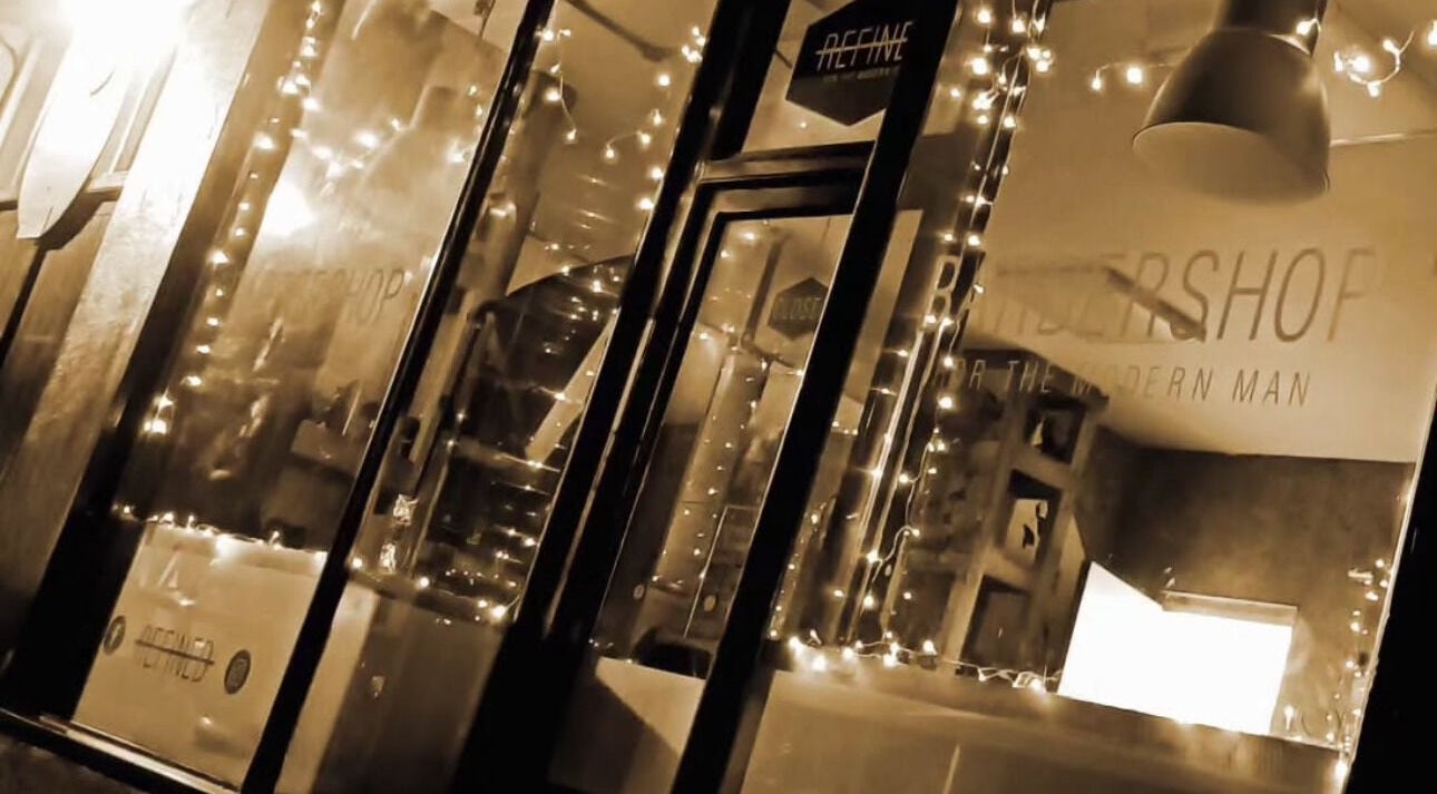 Illuminated exterior of REFINED BARBERSHOP, Paignton, England, GB with decorative lights.