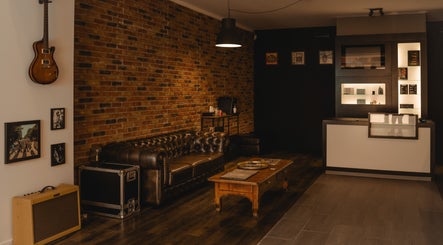 Industriële lounge met leren bank bij REBEL. Piercing Studio, Uden, Noord-brabant, NL.
