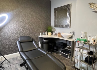 Modern treatment room at Aura Aesthetics, Leeds, England, GB. Equipped with chair, mirror, and skincare products.