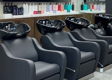 Cadeiras de lavagem no salão Brazil Studio Salon em Manama, BH, com produtos capilares ao fundo.