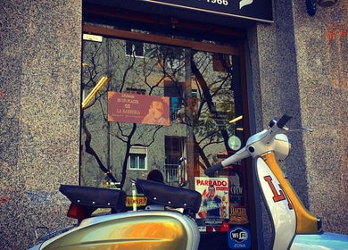 Fachada de La Barberia Desde 1966 en Barcelona, Catalunya, ES, con una vespa vintage afuera.