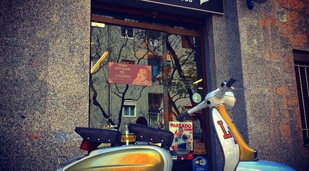 Fachada de La Barberia Desde 1966 en Barcelona, Catalunya, ES, con una vespa vintage afuera.