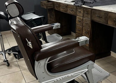 Luxe kappersstoel in De Kapper Elewijt, Zemst, Vlaanderen, BE met houten meubels op achtergrond.