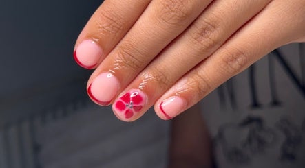 Stylish floral nail art at BySorayah, Birmingham, England, GB. Red tips and flower accent on natural polish.