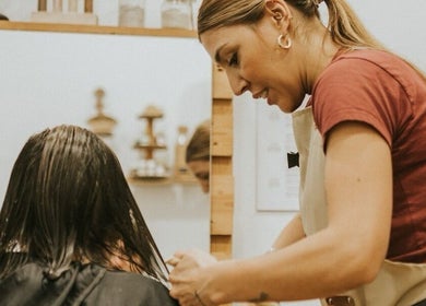 Estilista trabajando en Biopeluqueria, Málaga, Andalucía, ES, ofreciendo corte de cabello ecológico.