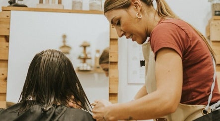 Estilista trabajando en Biopeluqueria, Málaga, Andalucía, ES, ofreciendo corte de cabello ecológico.