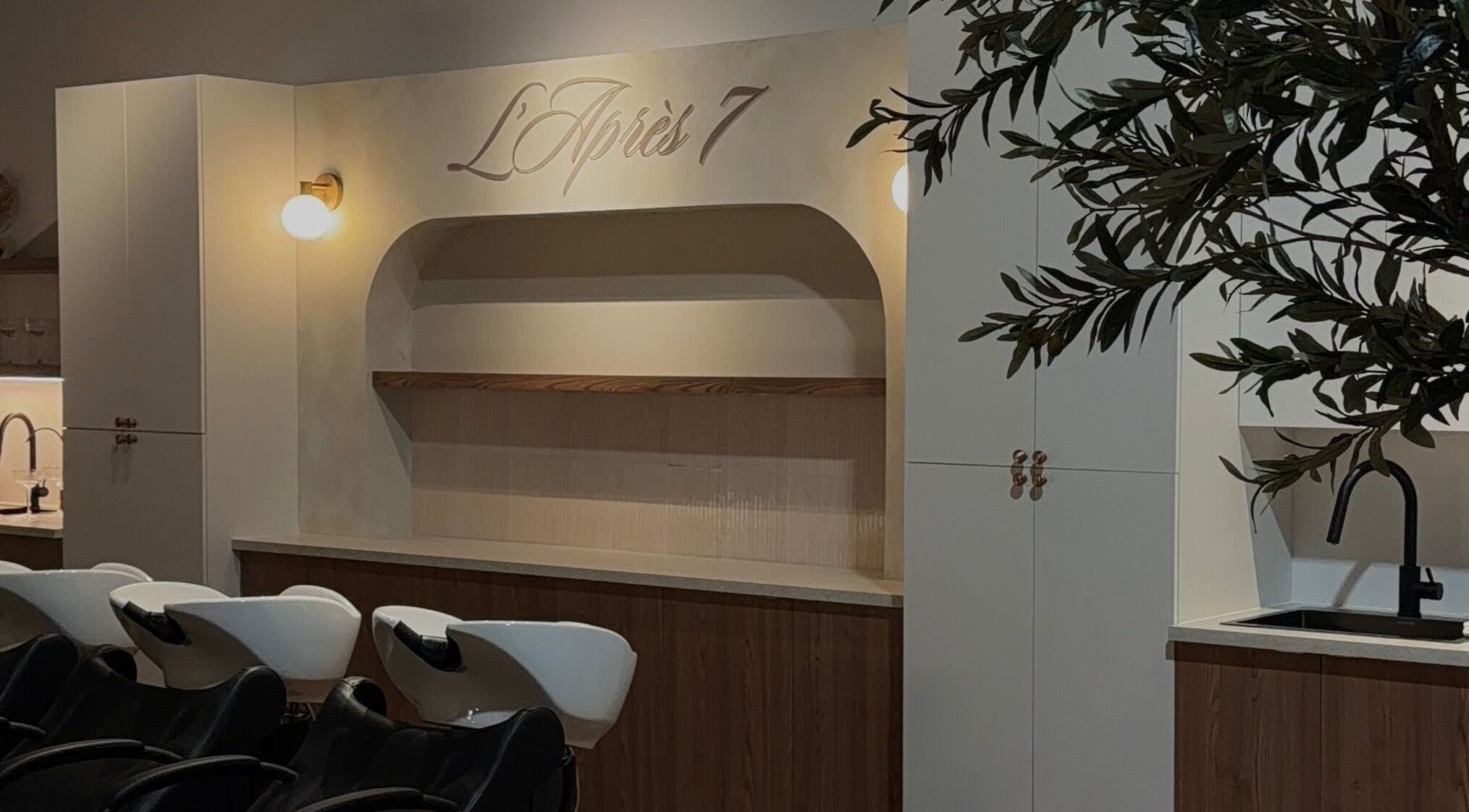 Intérieur élégant de L'Après 7 à Saint-Eustache, Québec, CA avec sièges de coiffure modernes.