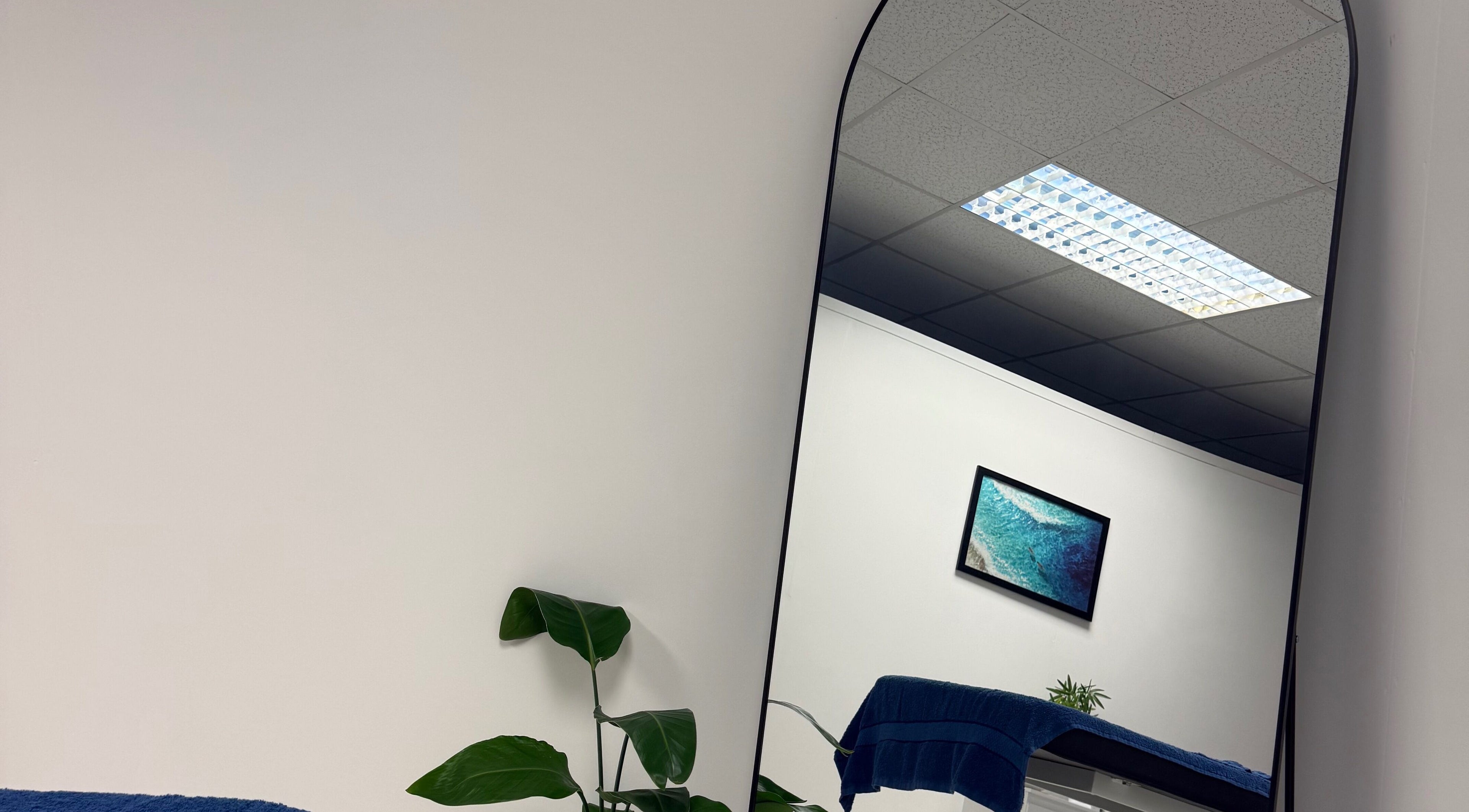 Elegant therapy room at CJ Flow Wellness, Milford Haven, Wales, GB, featuring a large mirror and minimalist decor.