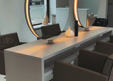 Intérieur moderne de MG Hairdresser à Schaerbeek, Bruxelles, BE avec miroirs éclairés et sièges confortables.