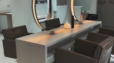 Intérieur moderne de MG Hairdresser à Schaerbeek, Bruxelles, BE avec miroirs éclairés et sièges confortables.