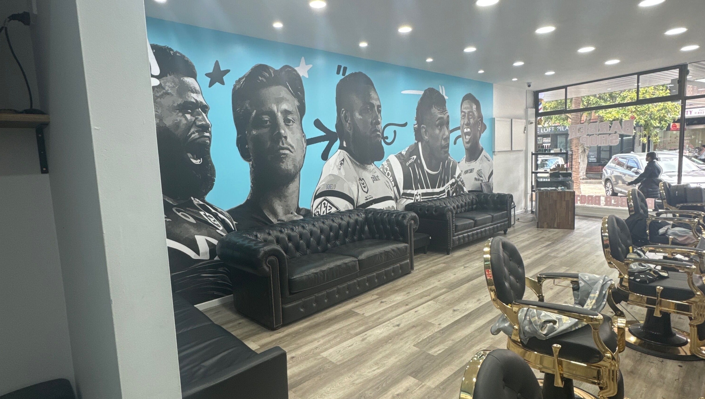 Stylish interior of Barber Brothers in Cronulla, New South Wales, AU, featuring a striking mural and plush seating.