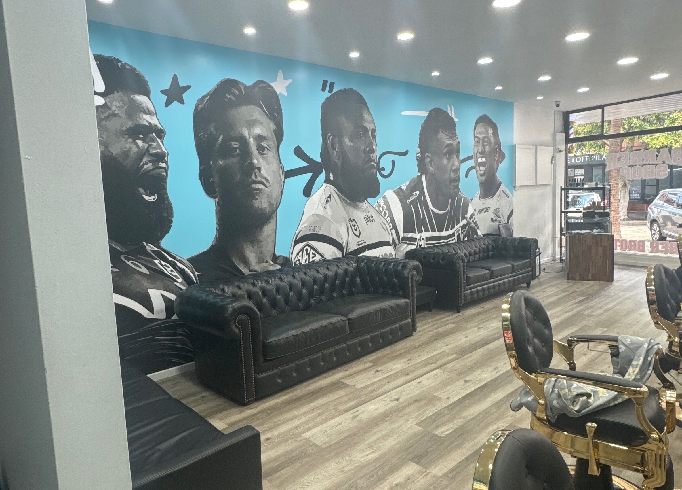 Stylish interior of Barber Brothers in Cronulla, New South Wales, AU, featuring a striking mural and plush seating.