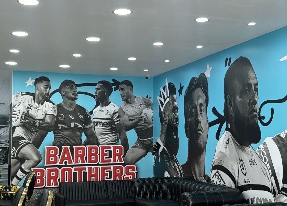 Inside Barber Brothers, Cronulla, New South Wales, AU, featuring sporty wall art and modern seating.