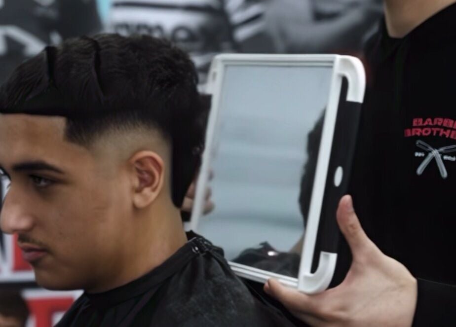 Customer at Barber Brothers in Cronulla, New South Wales, AU showing off a fresh haircut with a handheld mirror.