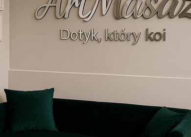 Wnętrze ArtMasaż w Poznaniu, Województwo Wielkopolskie, PL z elegancką sofą i logo na ścianie.