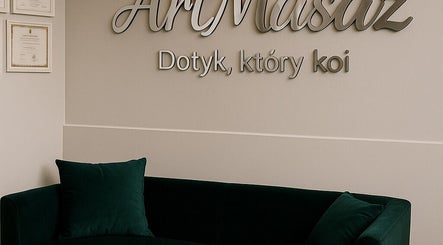 Wnętrze ArtMasaż w Poznaniu, Województwo Wielkopolskie, PL z elegancką sofą i logo na ścianie.