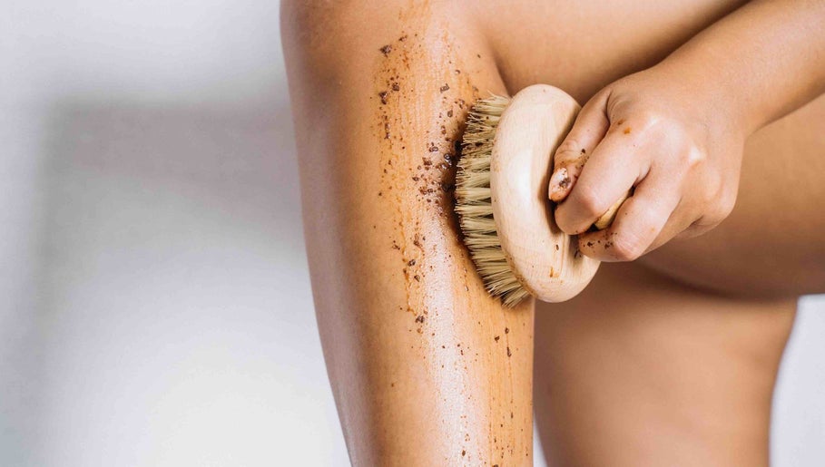 A person exfoliating leg with a brush at lv4, Southlake, Texas, US for smooth skin.