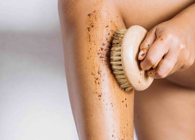A person exfoliating leg with a brush at lv4, Southlake, Texas, US for smooth skin.