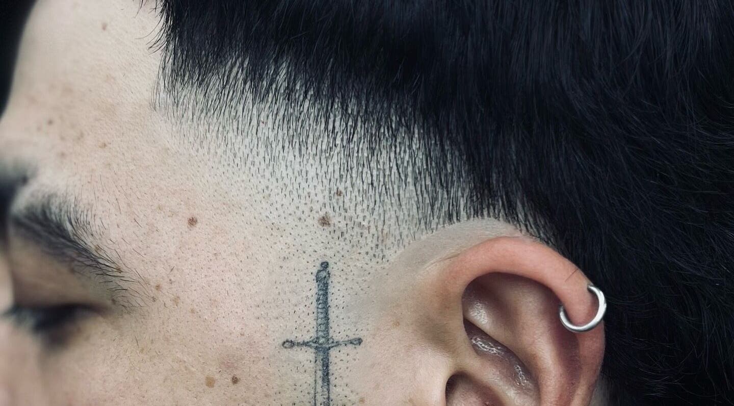 Corte de pelo moderno en Elegant Barber, Risaralda, Risaralda, CO, con detalle de tatuaje y pendiente.