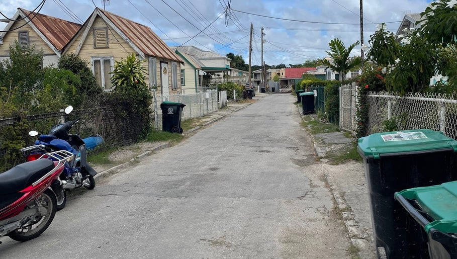 Charming street view near Nya_nailluxury, Bridgetown, Saint Michael, BB, featuring quaint houses and scooters.