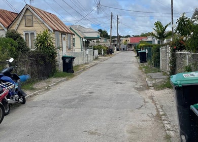 Charming street view near Nya_nailluxury, Bridgetown, Saint Michael, BB, featuring quaint houses and scooters.