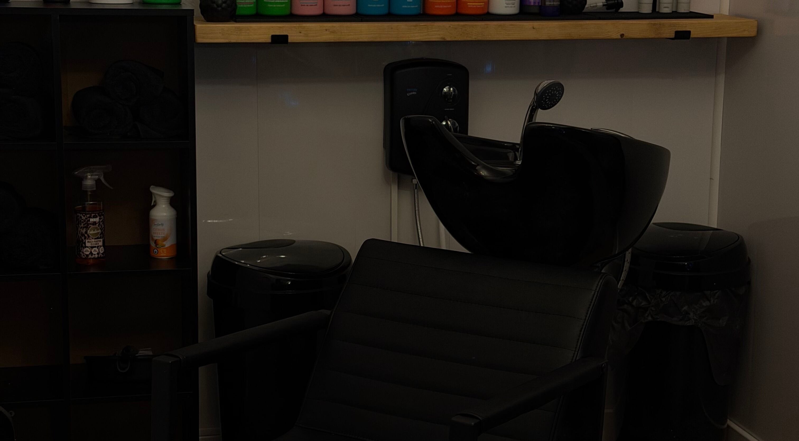 Modern wash station at The House Of Hair & Beauty, Wolverhampton, England, GB, with organized shampoo bottles.