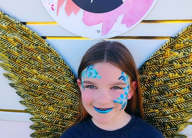 Child with vibrant face paint and golden wings at Faces of Angels, Hartlepool, England, GB.
